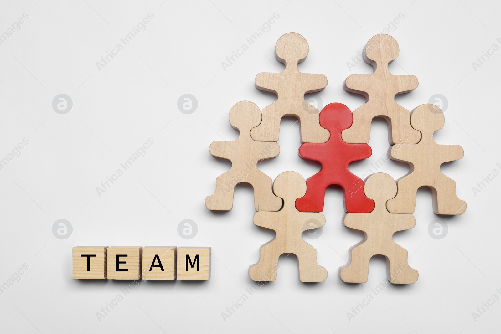 Photo of Red figure among wooden ones and cubes with word Team on white background, flat lay. Recruiter searching employee