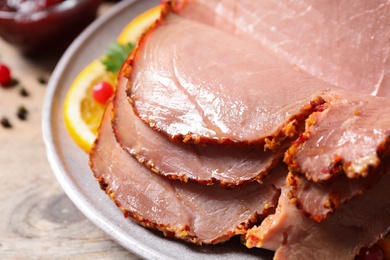 Delicious ham served with garnish on wooden table, closeup