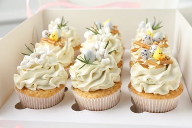 Photo of Tasty Easter cupcakes with vanilla cream in box, closeup