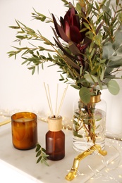 Photo of Reed air freshener with candle and bouquet on  marble tray