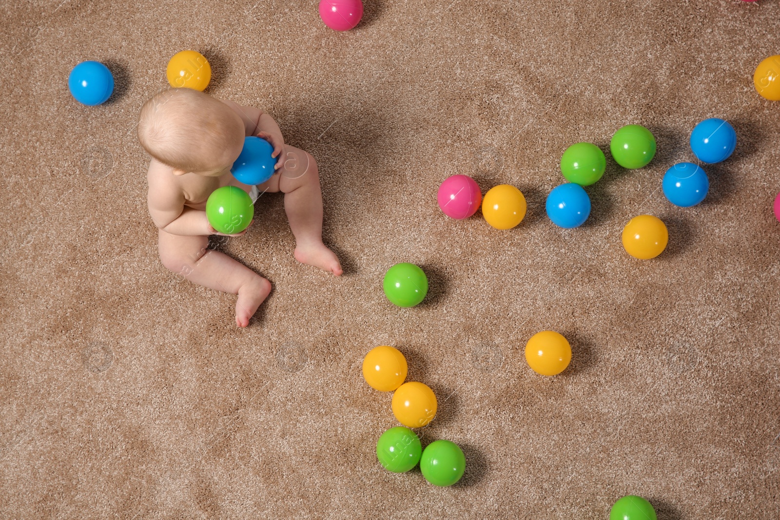 Photo of Cute little baby crawling on carpet with toys, top view