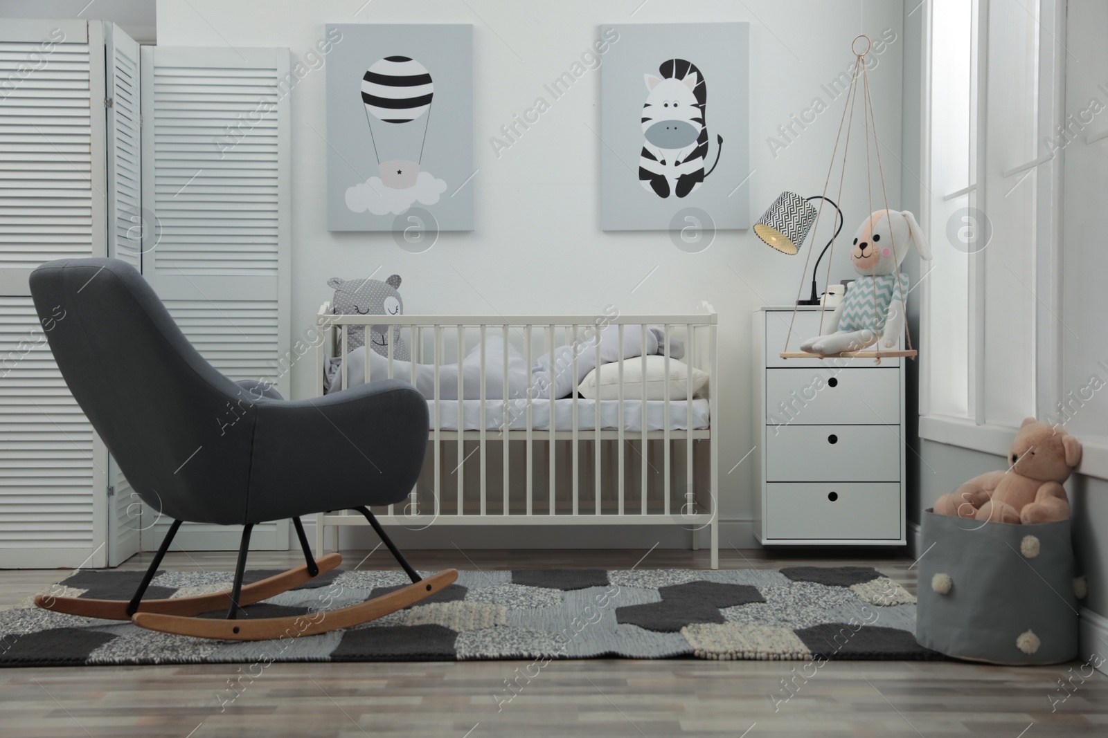 Photo of Stylish baby room interior with crib and rocking chair