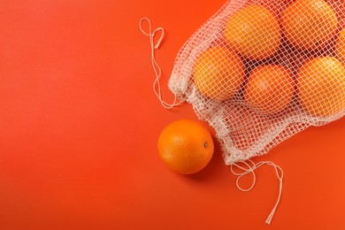 Net bag with fresh oranges on color background, top view. Space for text