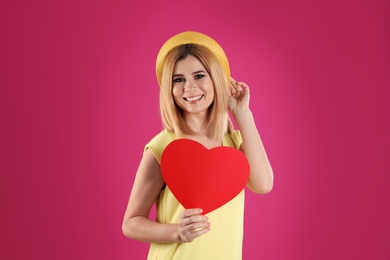 Beautiful woman with paper heart on color background