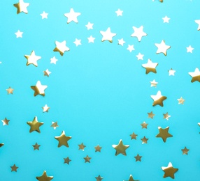 Frame made of confetti stars with space for text on blue background, top view. Christmas celebration