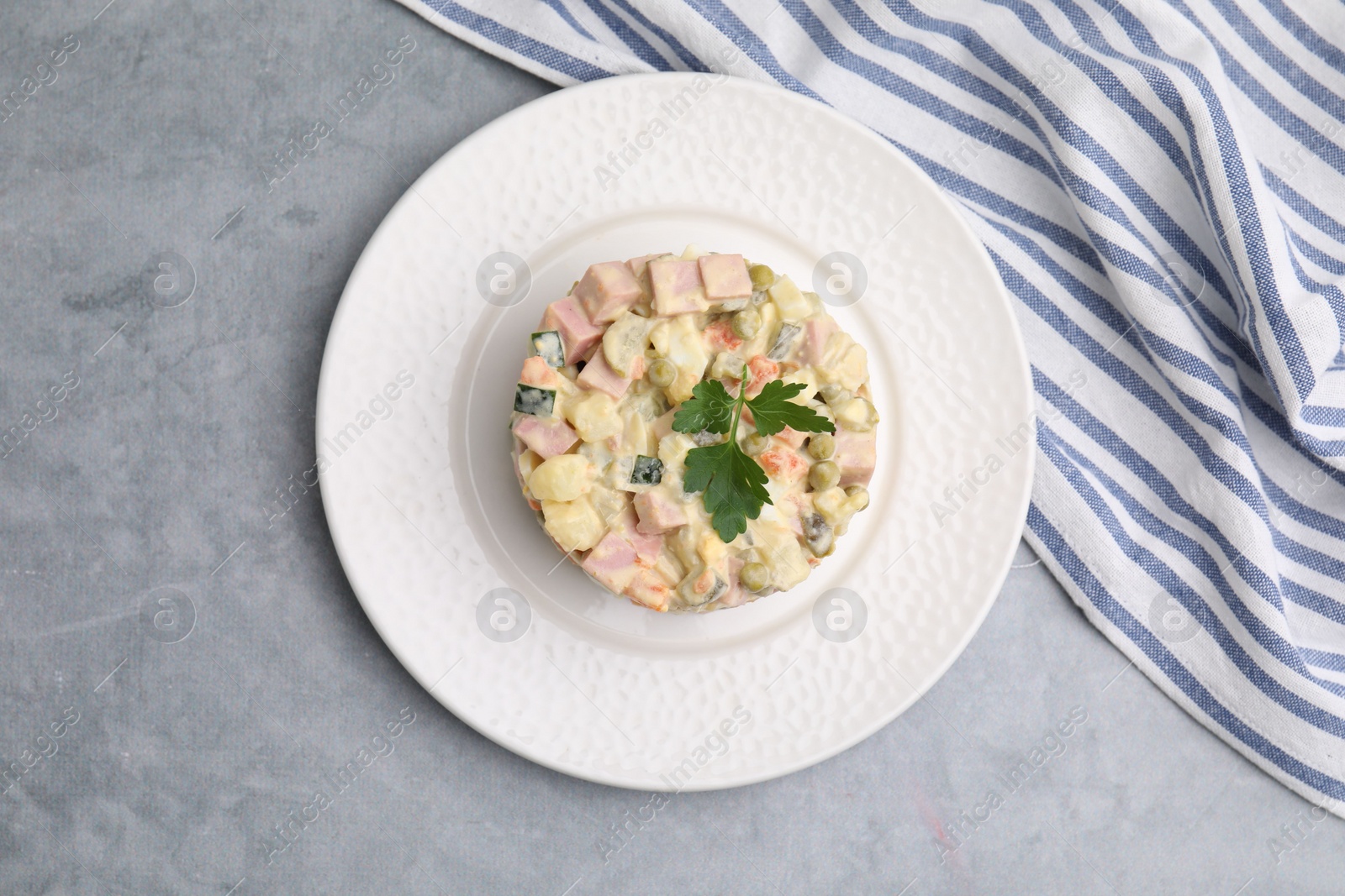 Photo of Tasty Olivier salad with boiled sausage on grey table, top view