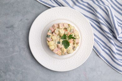 Photo of Tasty Olivier salad with boiled sausage on grey table, top view