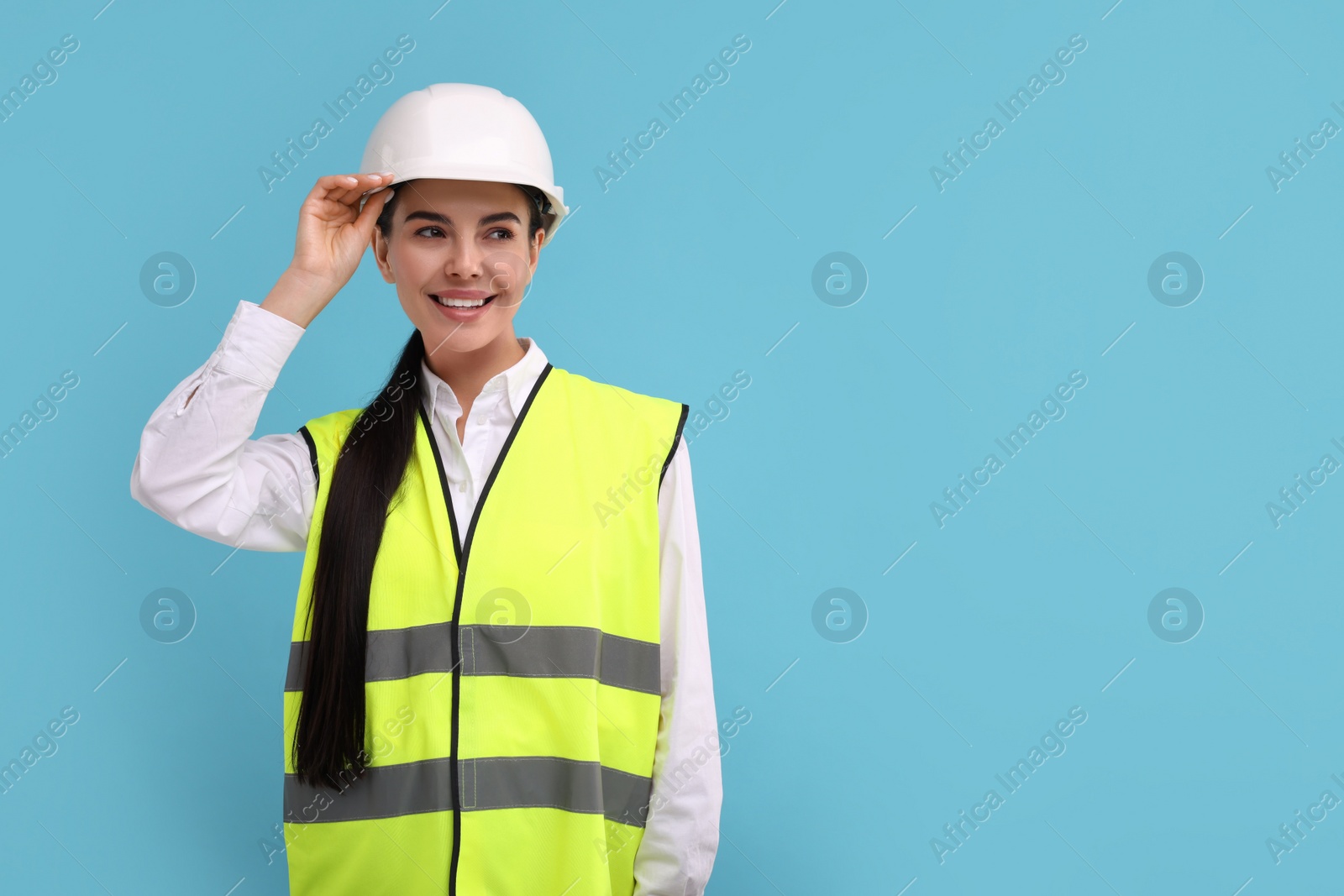 Photo of Engineer in hard hat on light blue background, space for text