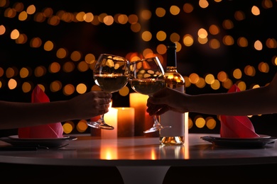 Photo of Couple with glasses of wine having romantic candlelight dinner at table, closeup