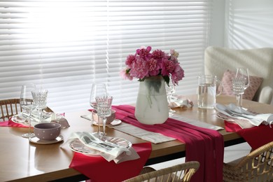 Photo of Pink peonies on table with beautiful setting in dining room