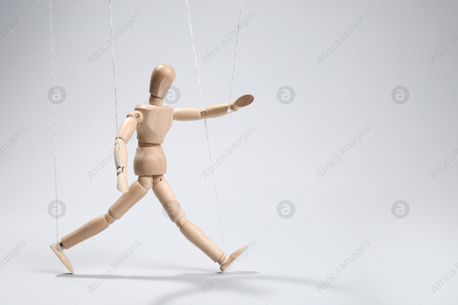 Photo of One wooden puppet with strings on light grey background