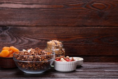 Photo of Tasty granola with nuts, different ingredients on wooden table. Space for text