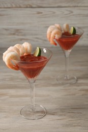 Tasty shrimp cocktail with sauce and lime in glasses on wooden table