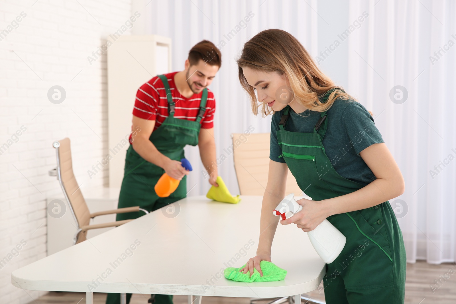 Photo of Professional janitors cleaning table in office. Hired help