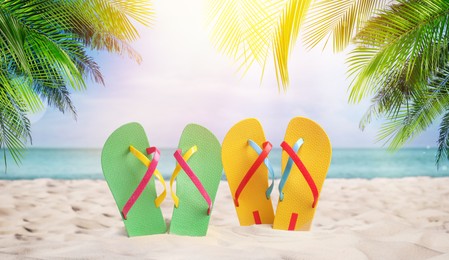 Image of Pairs of bright flip flops on sandy beach near sea 