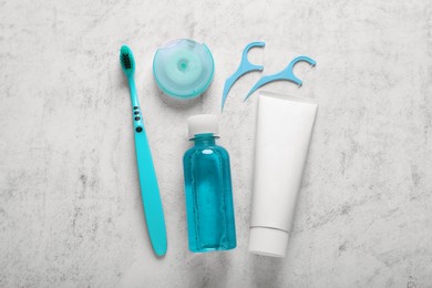 Photo of Flat lay composition with dental floss and different teeth care products on light grey textured table