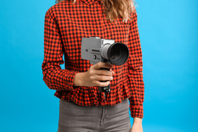 Photo of Woman with vintage video camera on light blue background, closeup