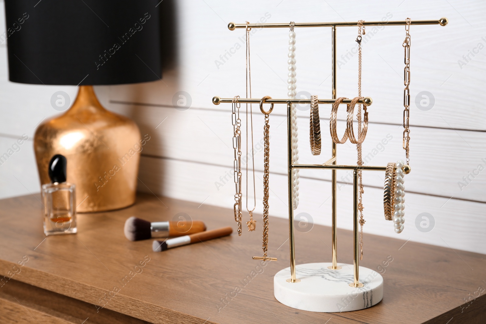 Photo of Holder with set of luxurious jewelry on wooden dressing table