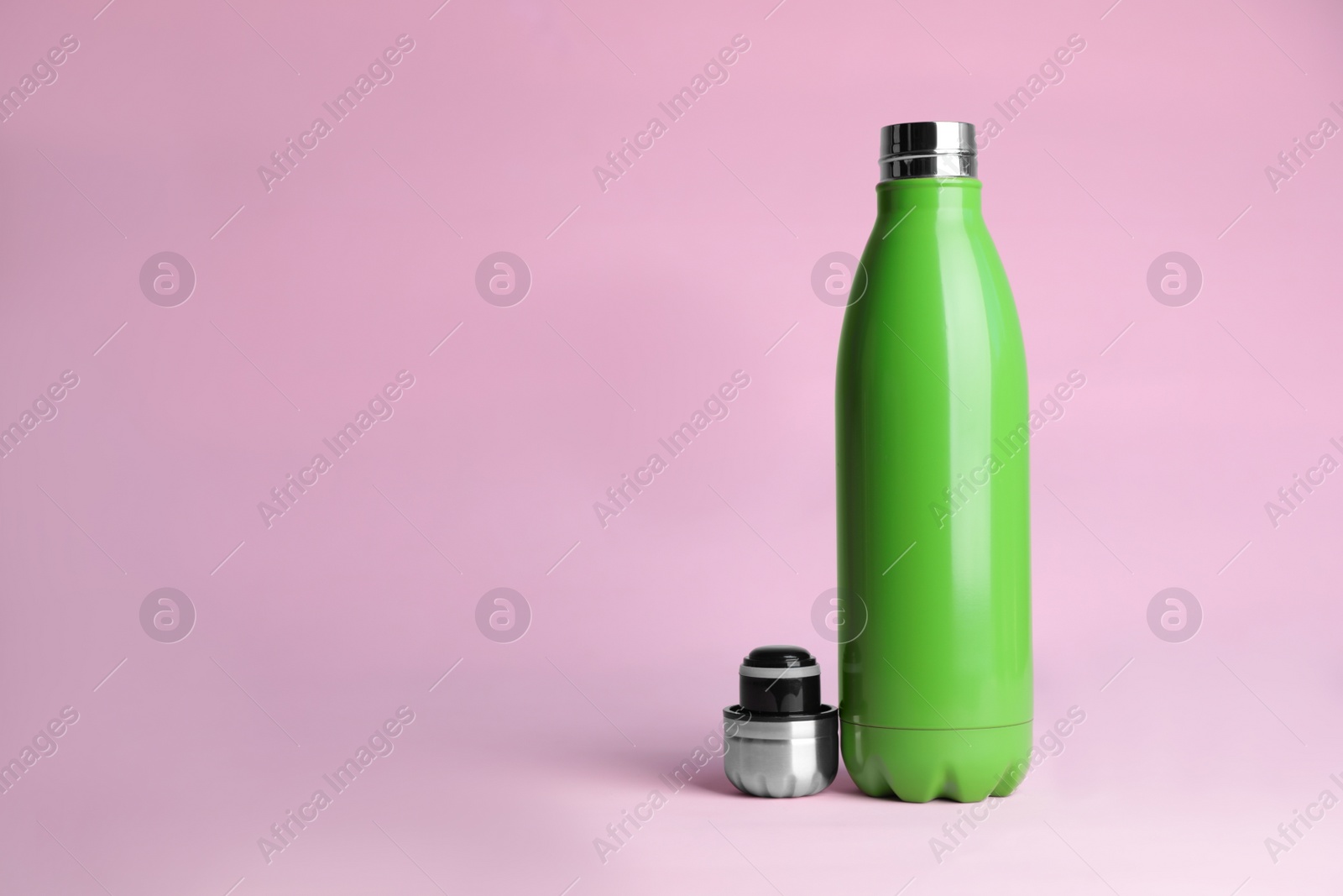 Photo of Stylish thermo bottle on pink background, space for text