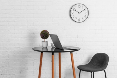 Room interior with table and analog clock hanging on wall. Time of day