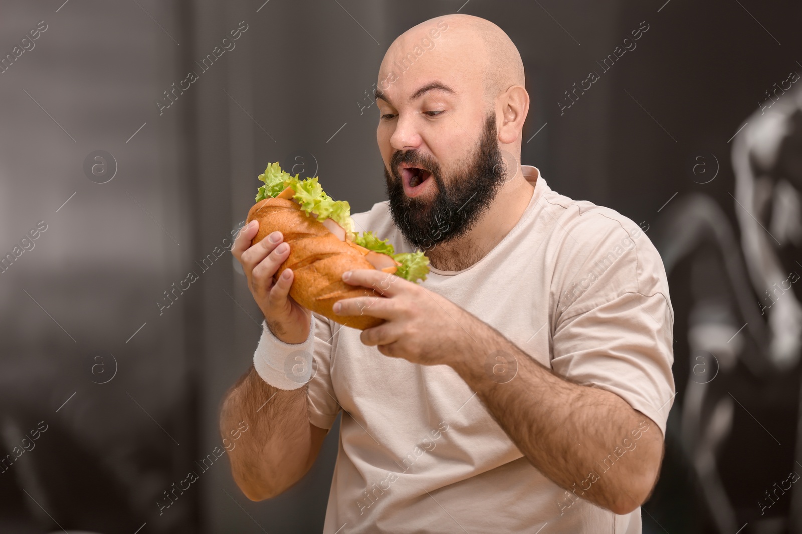 Photo of Overweight man eating sandwich in gym