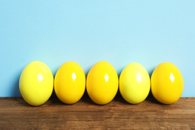 Photo of Easter eggs on wooden table against light blue background
