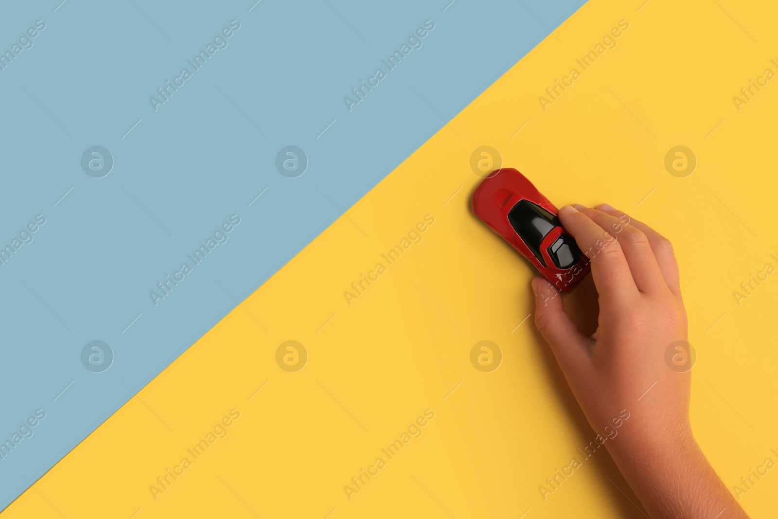 Photo of Child playing with toy car on color background, top view. Space for text