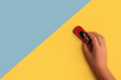 Photo of Child playing with toy car on color background, top view. Space for text