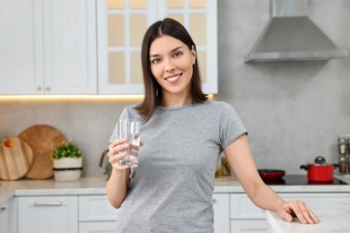 Woman with glass of fresh water in kitchen