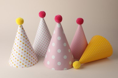 Photo of Beautiful party hats with pompoms on beige background