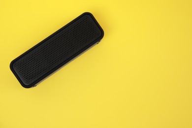 Photo of One portable bluetooth speaker on yellow background, top view with space for text. Audio equipment