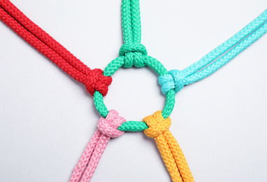 Photo of Colorful ropes tied together on white background, top view. Unity concept