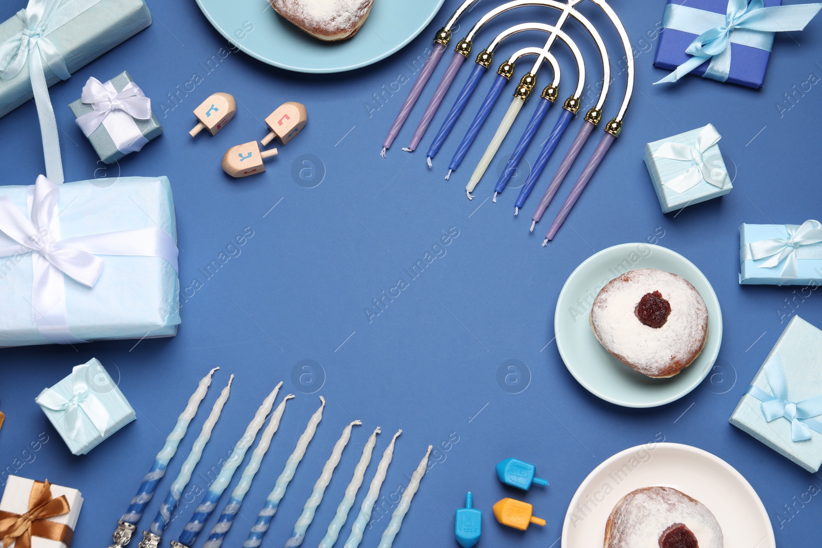 Photo of Frame of Hanukkah menorah, dreidels and gift boxes on blue background, flat lay. Space for text