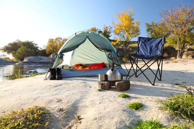 Photo of Camping equipment near tent with sleeping bag outdoors