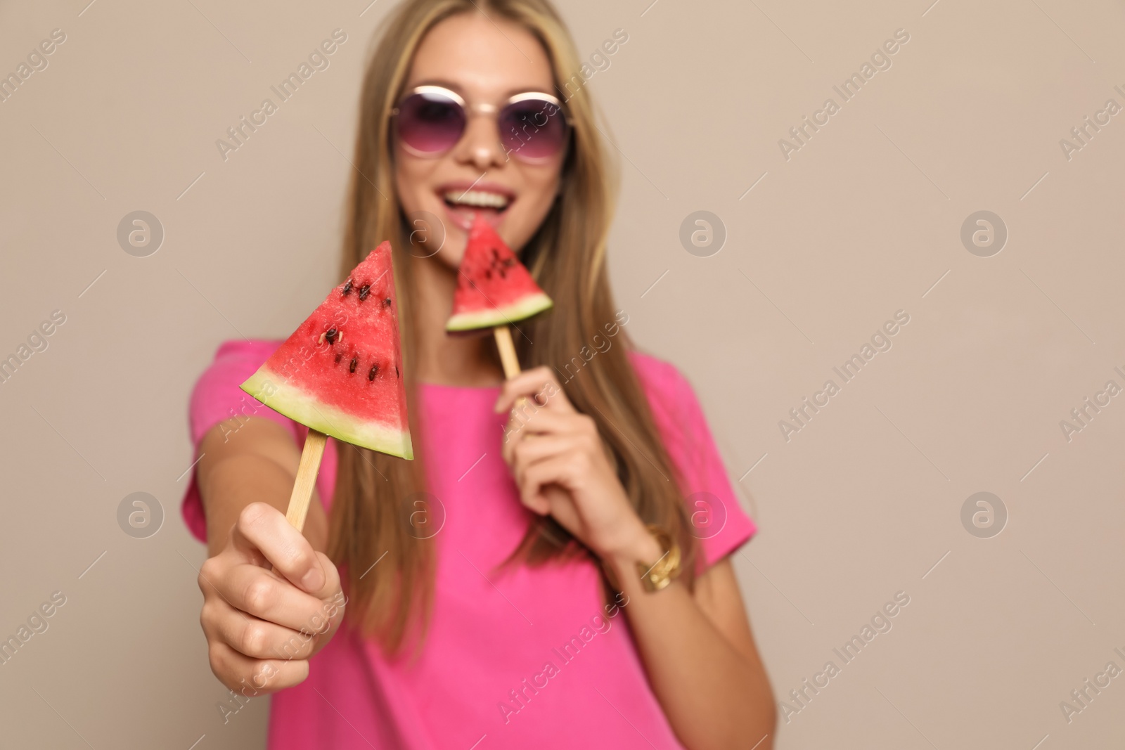 Photo of Beautiful girl with pieces of watermelon against beige background, focus on hand