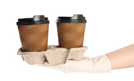 Woman holding cardboard holder with takeaway paper coffee cups on white background, closeup