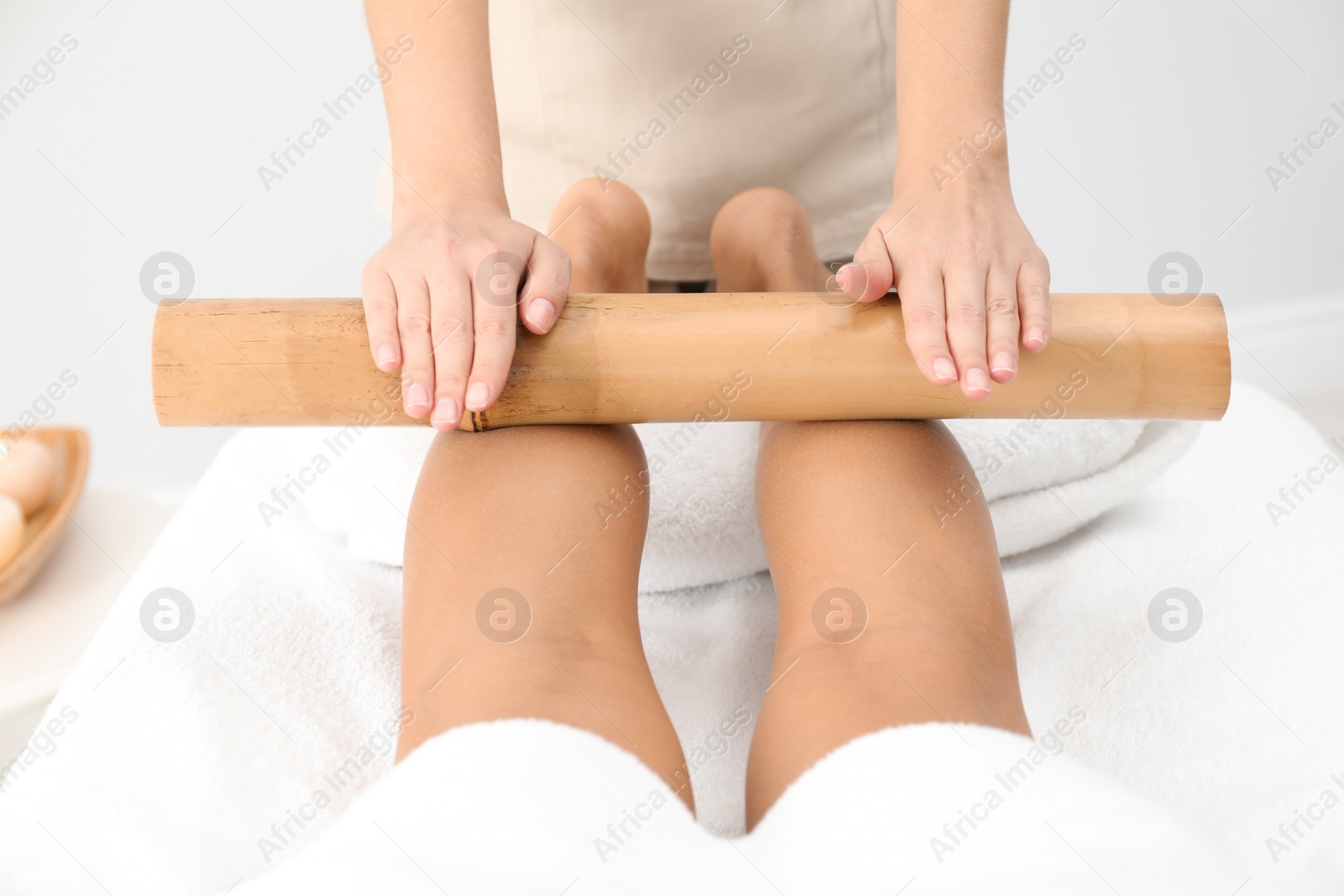 Photo of Woman having massage with bamboo stick in wellness center, closeup