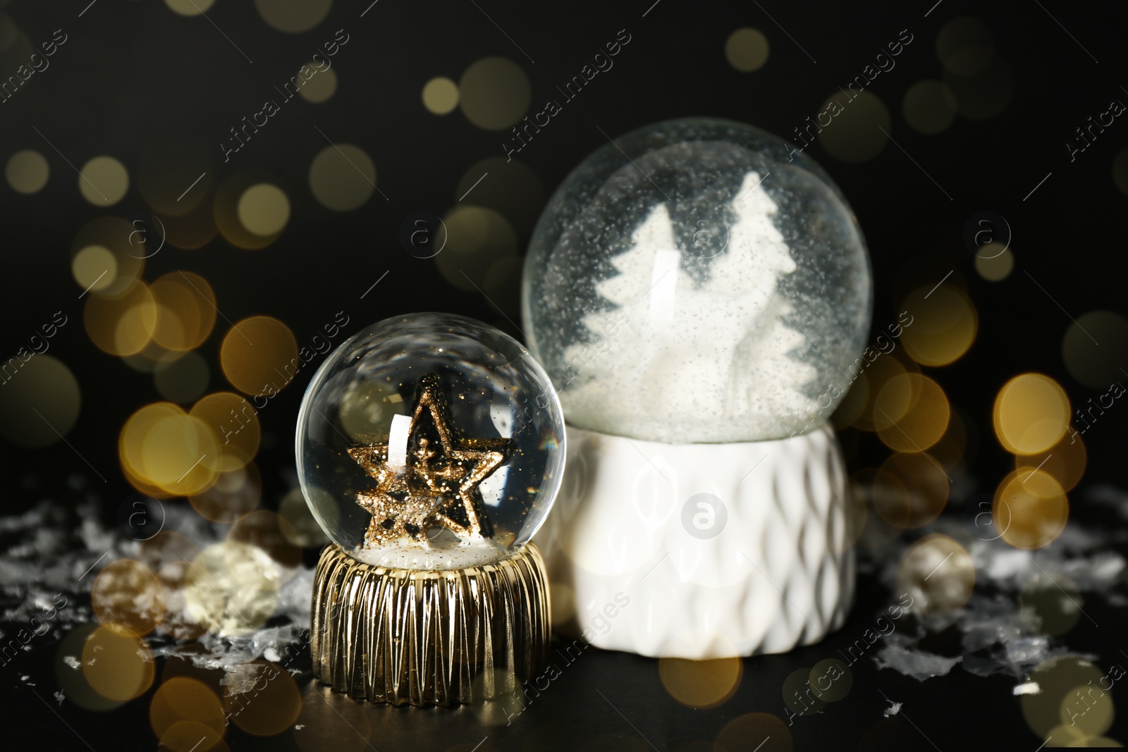 Image of Beautiful Christmas snow globes on black background, bokeh effect