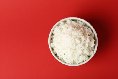 Photo of Bowl of boiled rice on color background, top view with space for text