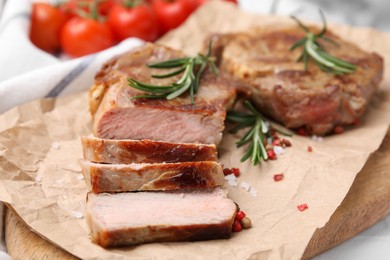 Photo of Delicious fried meat with rosemary and spices on wooden board, closeup