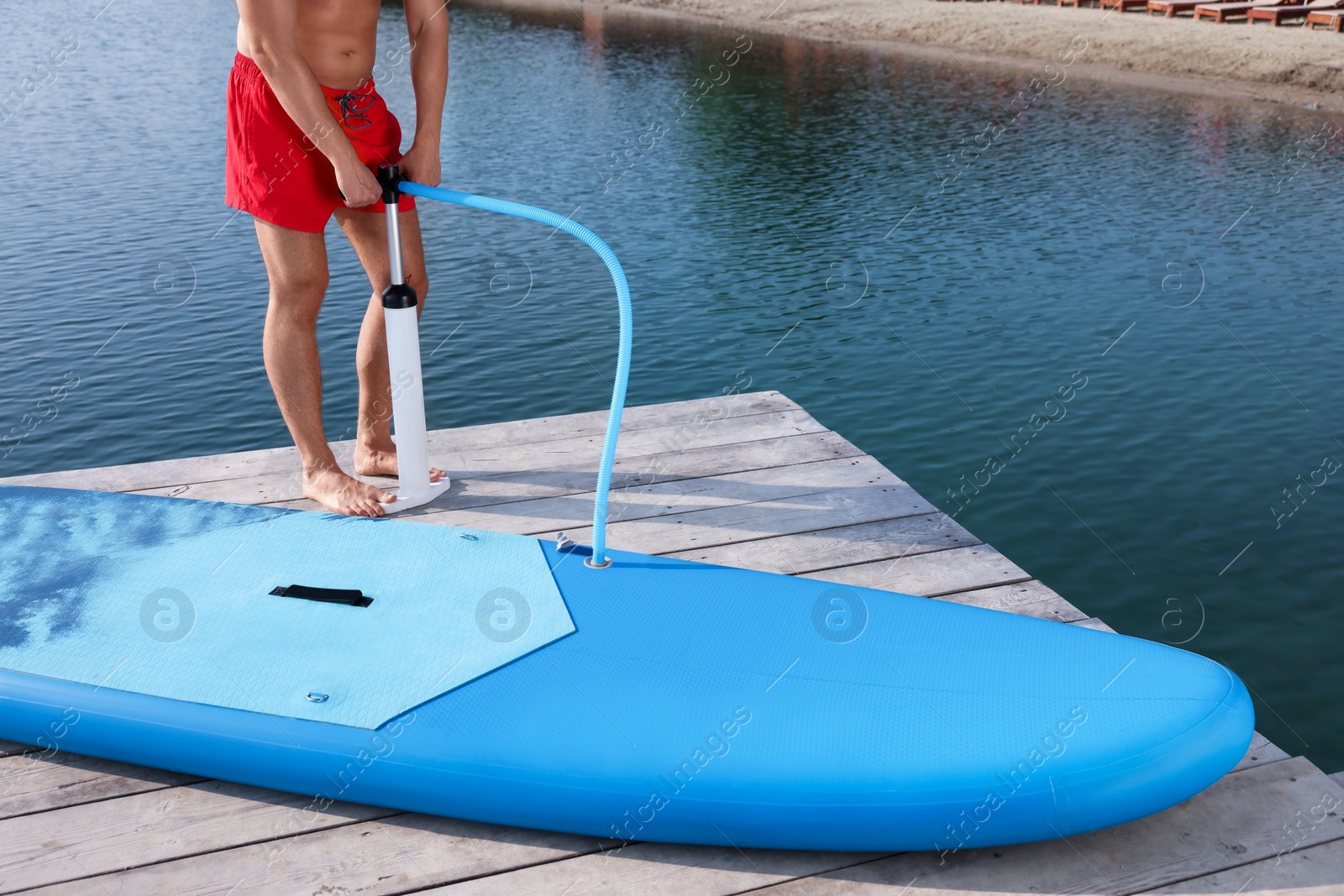 Photo of Man pumping up SUP board on pier, closeup
