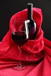 Photo of Stylish presentation of delicious red wine in bottle and glass on table against black background