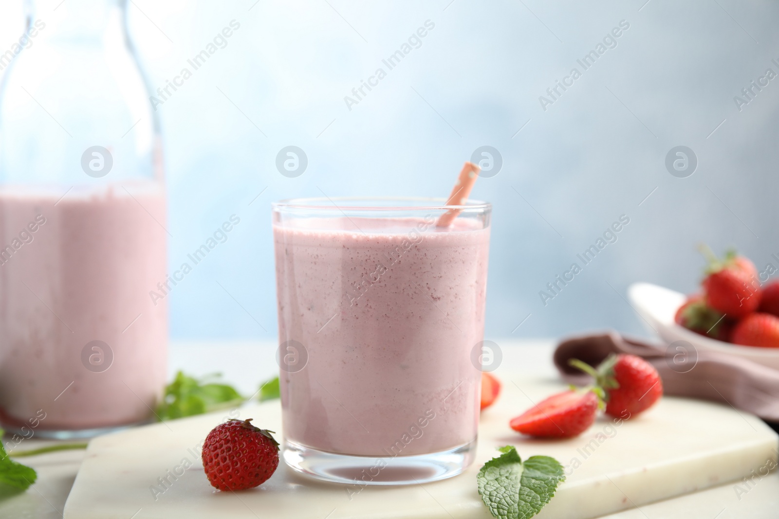 Photo of Tasty milk shake with strawberries and mint on white marble board