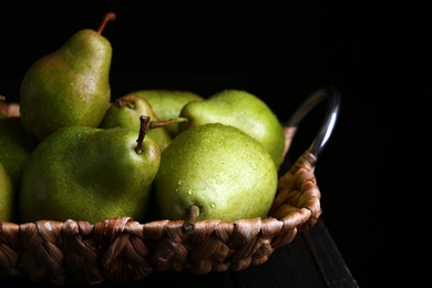 Tray with ripe pears on wooden table against dark background, closeup