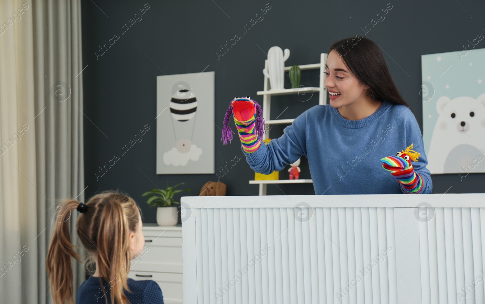 Photo of Mother performing puppet show for her daughter at home