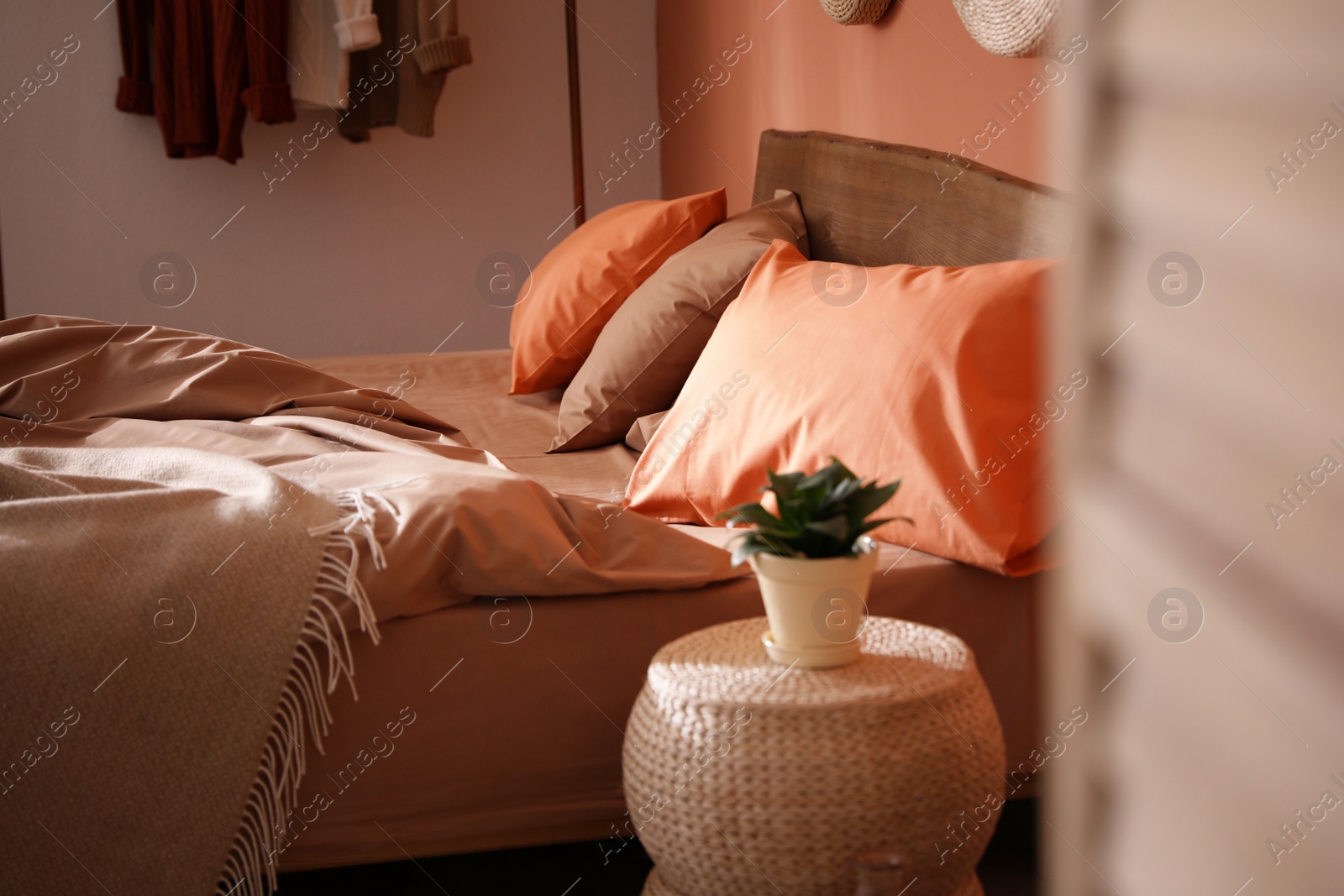 Photo of Bed with orange and brown linens in stylish room