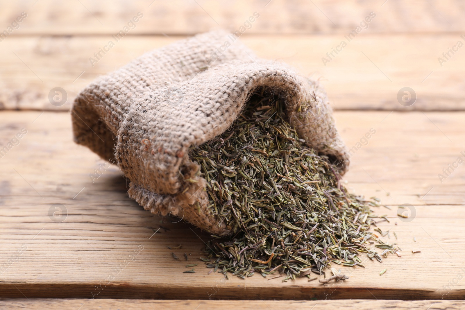 Photo of Sack with dried thyme on wooden table, closeup
