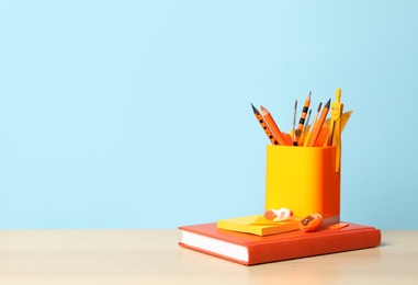 Photo of Composition with different school stationery on wooden table against light blue background, space for text. Back to school