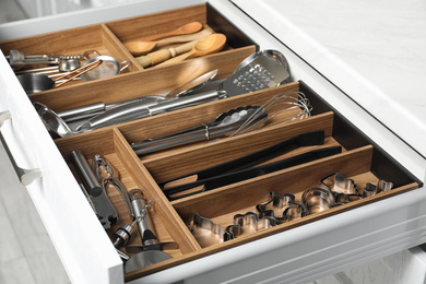 Different utensils in open desk drawer indoors