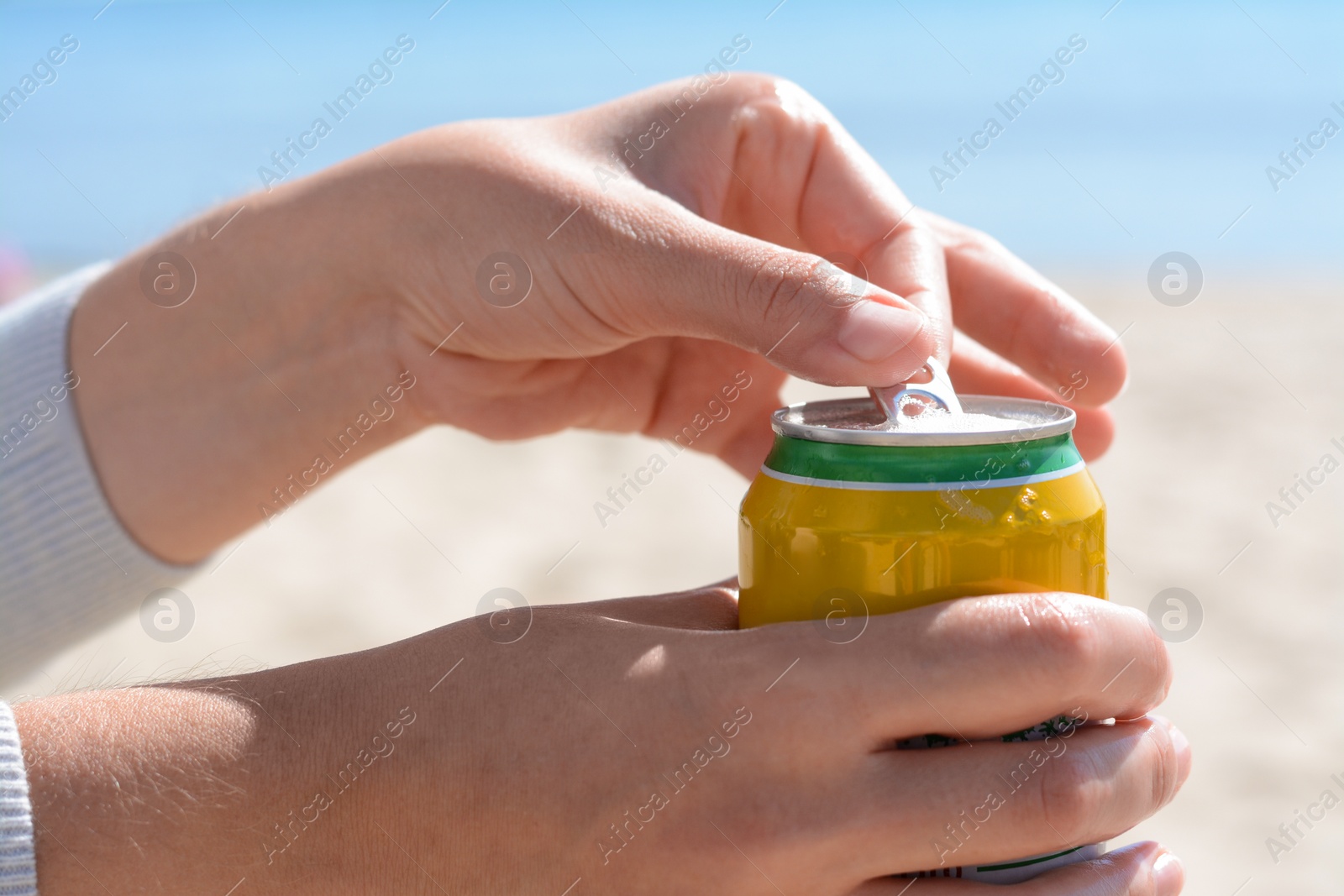 Photo of Woman opening can with sparkling drink at beach, closeup